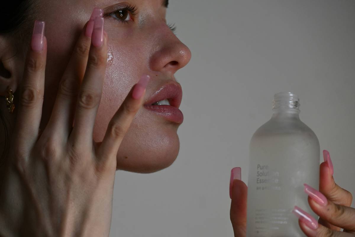 Woman applying hydrating moisturizer for body to her arms after a shower