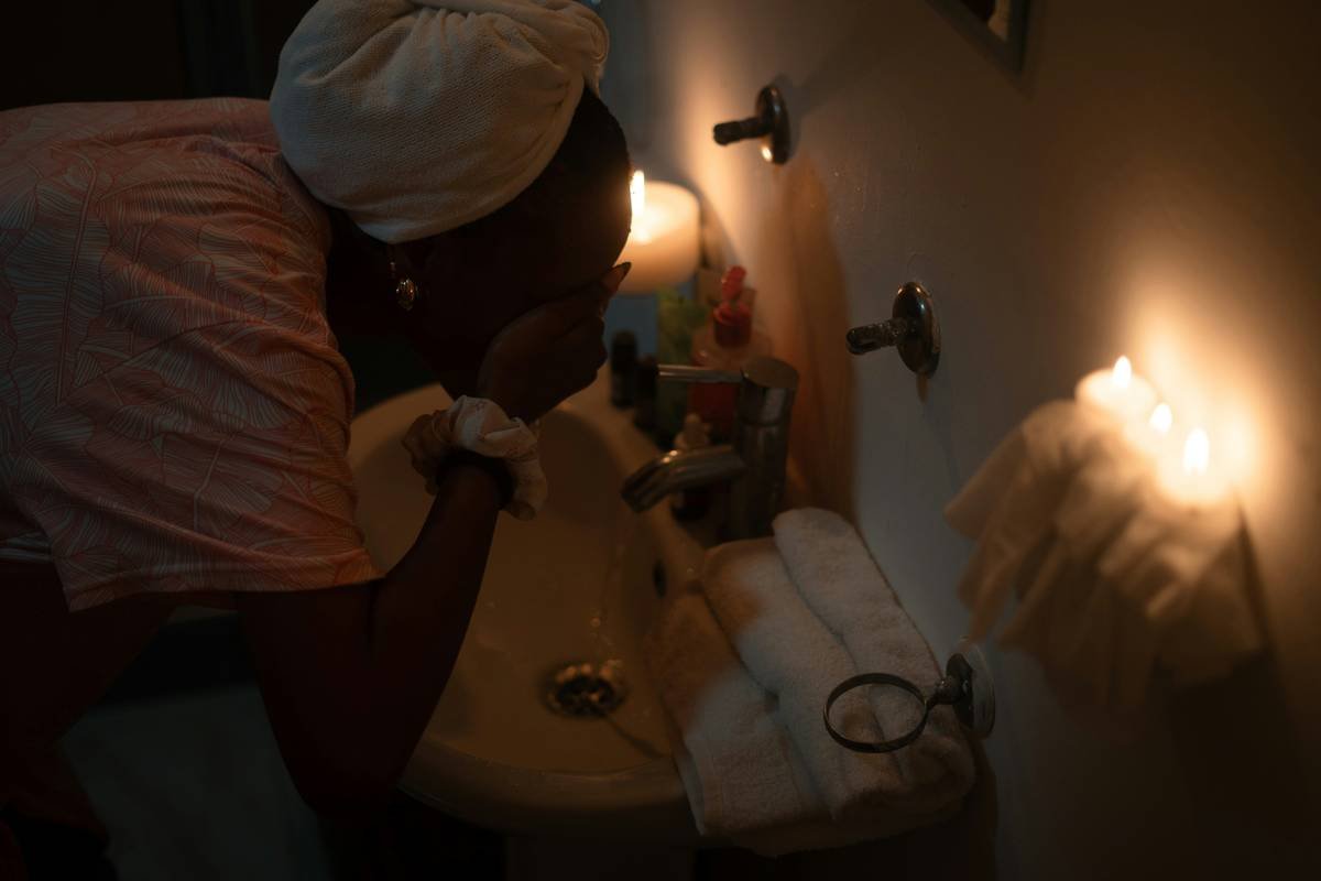 Woman applying everyday vulva moisturizer to clean, dry skin in a well-lit bathroom